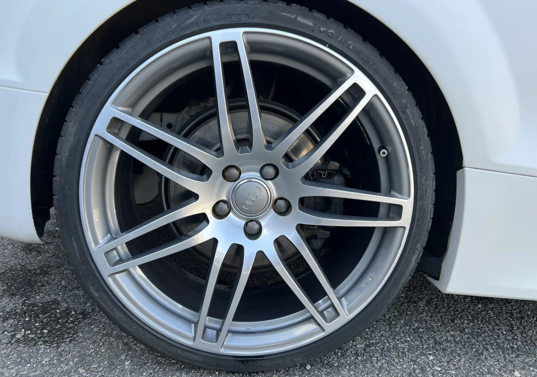 Gros plan sur la jante alliage argentée de l'Audi TT RS Roadster blanc, mettant en valeur le logo Audi au centre.