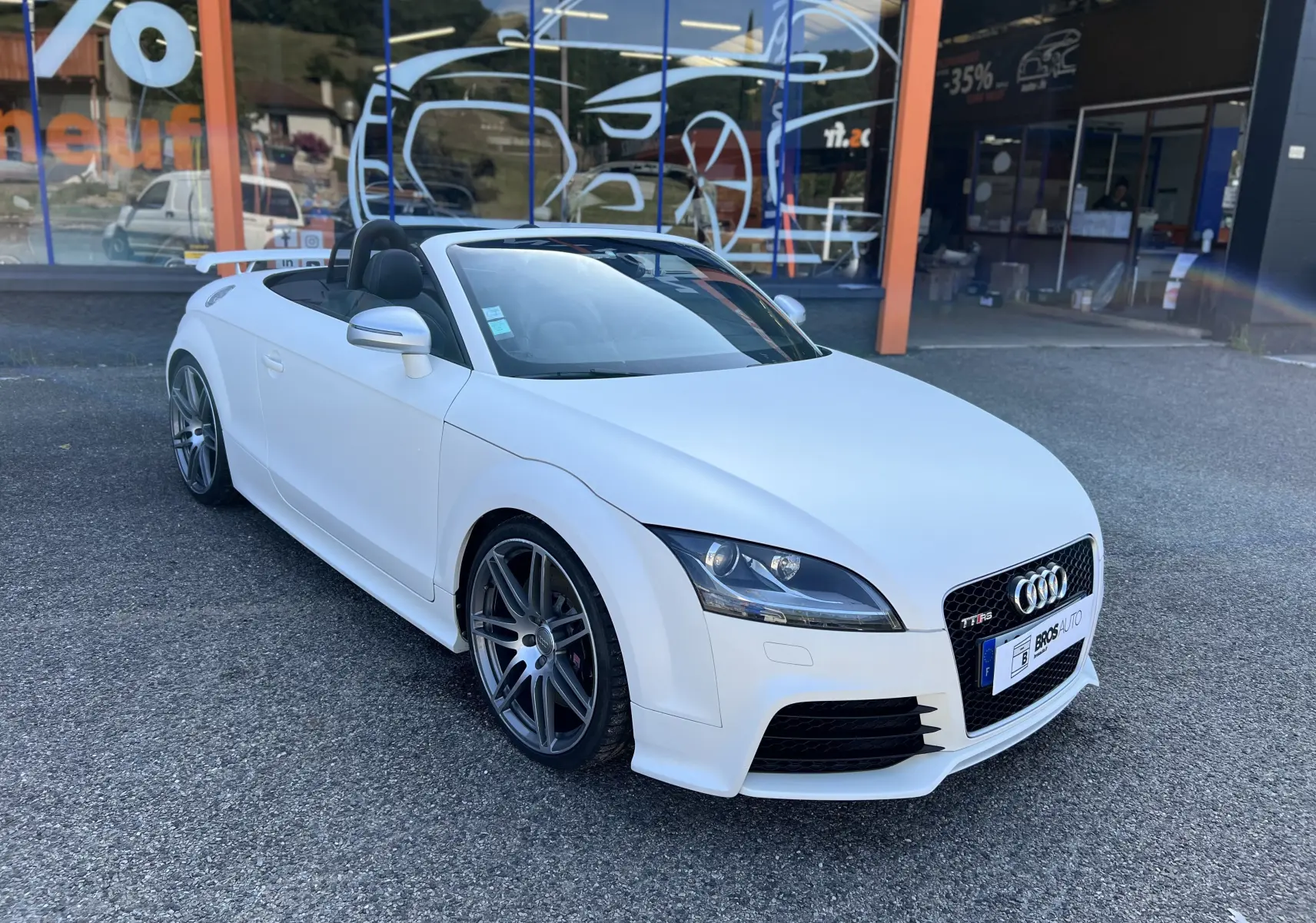 Audi TT RS Roadster blanc vue 3/4 avant droit, cabriolet avec jantes sport et intérieur noir visible.