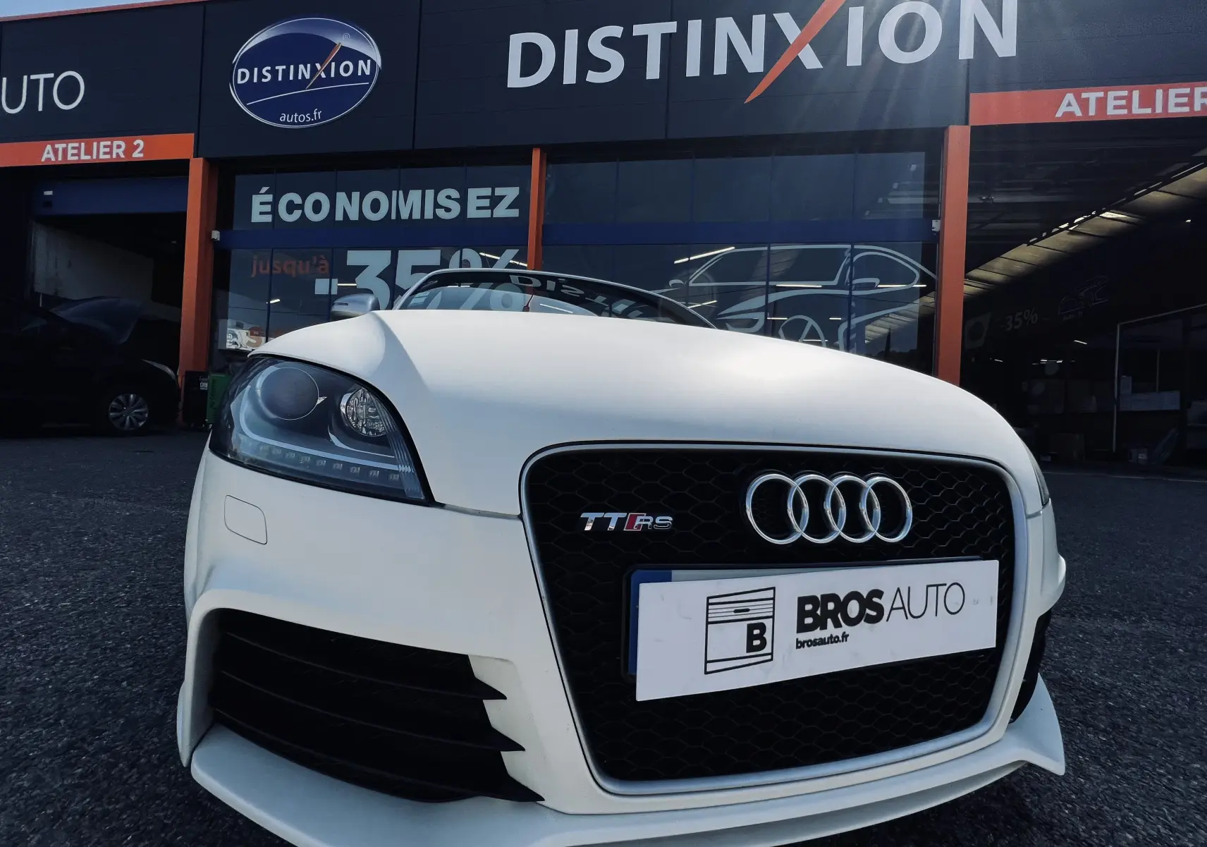 Vue avant rapprochée d'un Audi TT RS Roadster blanc avec calandre noire et logo quatre anneaux visible.