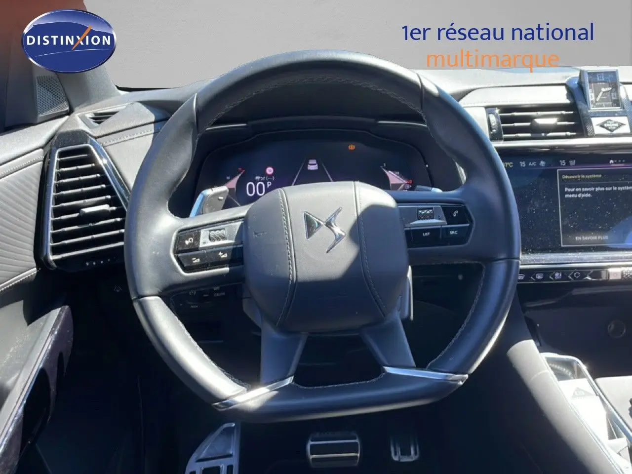 Vue rapprochée du volant cuir noir du DS7 2024, avec tableau de bord numérique et écran tactile visible à droite.