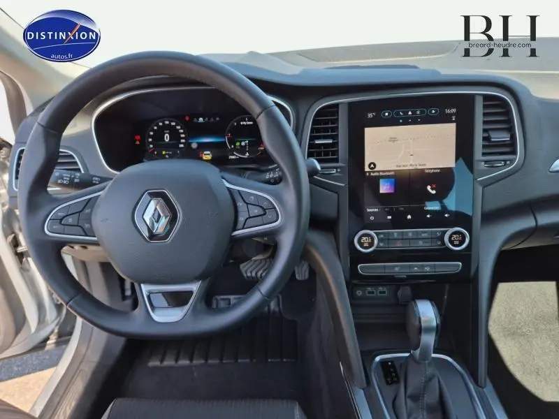 Vue intérieure du poste de conduite de la Renault Megane Break 2024, volant multifonction et écran tactile central.