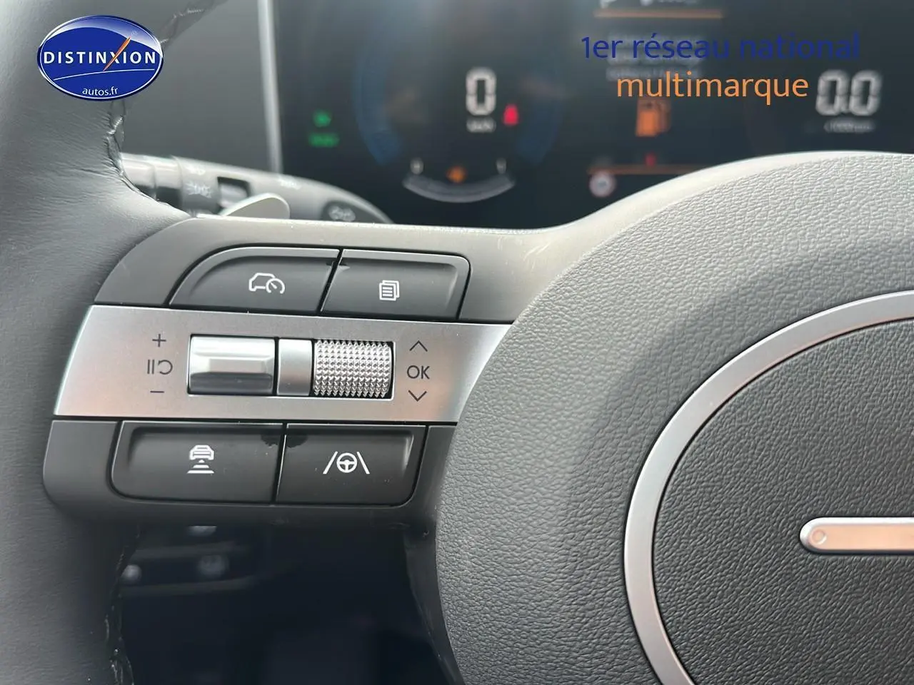 Gros plan sur les commandes à gauche du volant cuir du Hyundai Tucson blanc Sérénité 2025 hybride.