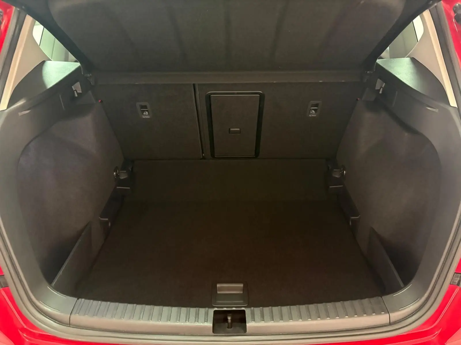 Coffre ouvert du SEAT Ateca Rouge Velvet 2024, montrant le plancher à double fond et l’espace de chargement vide.