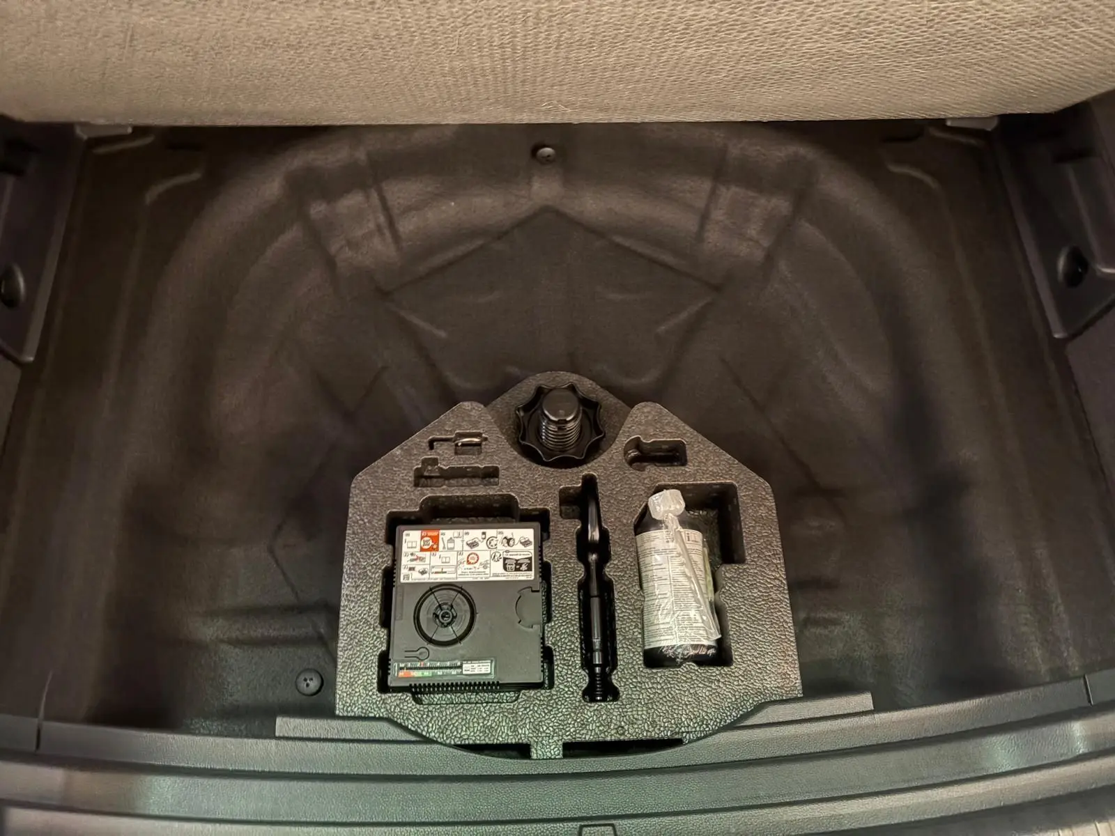 Vue plongeante sur le plancher de coffre à double fond du SEAT Ateca 2024, avec kit de réparation visible.