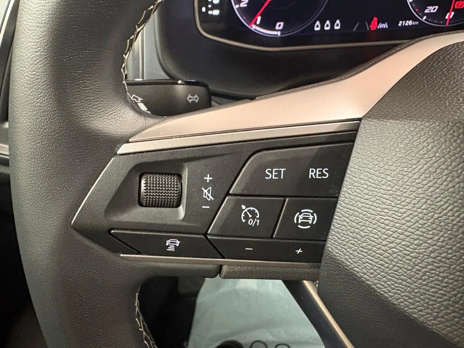 Vue rapprochée du volant côté gauche du SEAT Ateca 2024 Rouge Velvet, montrant les commandes de régulateur de vitesse.