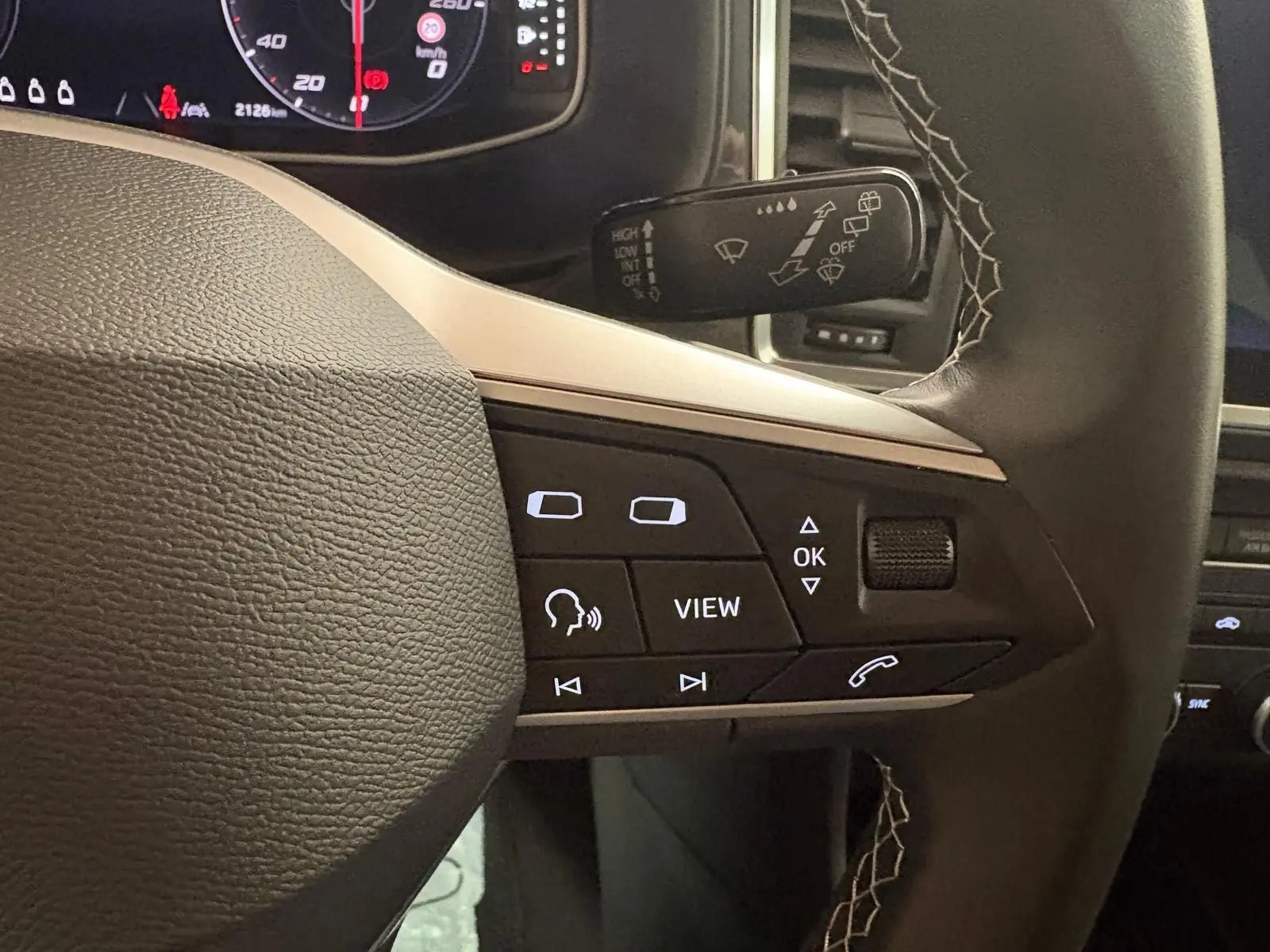 Gros plan sur les commandes au volant du SEAT Ateca 2024, mettant en valeur les boutons multifonctions et le cuir noir.