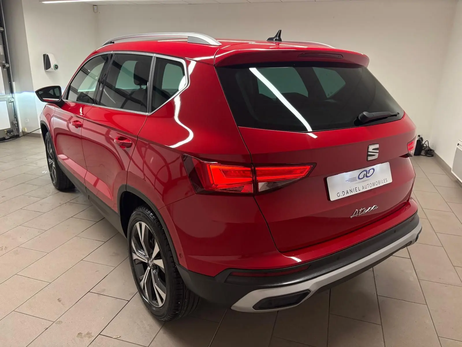 Vue 3/4 arrière droite du SEAT Ateca Rouge Velvet 2024 avec feux allumés et jantes alliage distinctives.