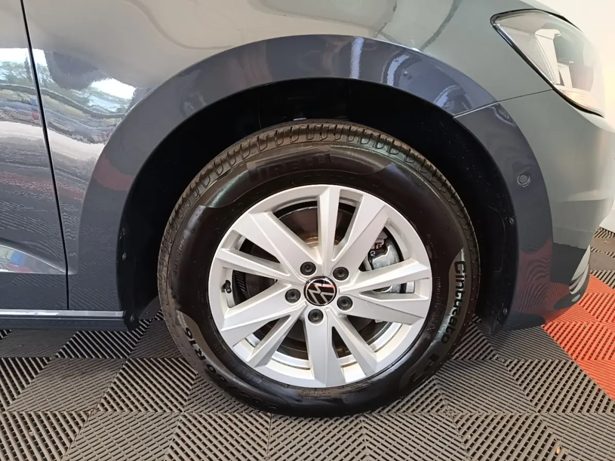 Gros plan sur la roue avant droite gris clair du Volkswagen Touran 2024 avec jante alliage et logo VW central.
