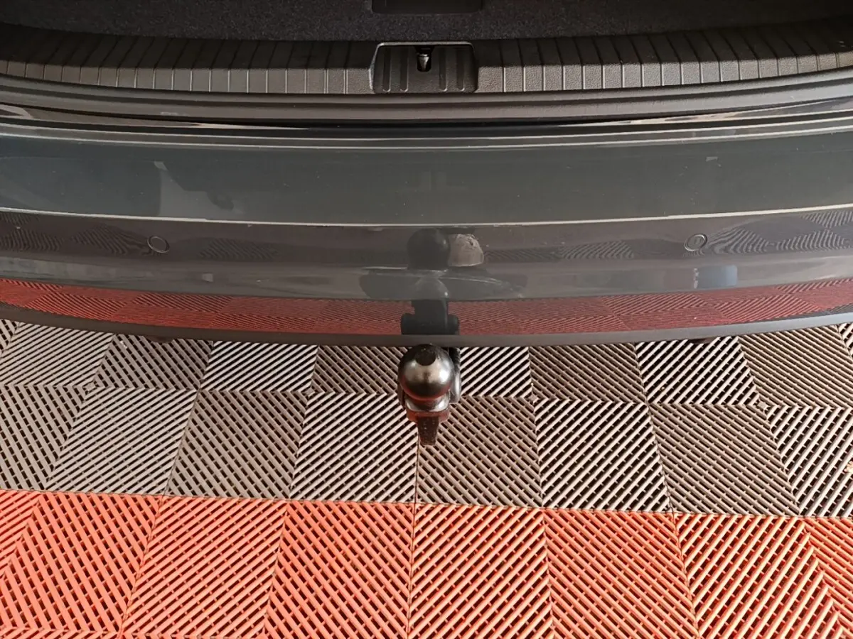 Vue rapprochée de l'attelage de remorque sous le pare-chocs arrière gris clair du Volkswagen Touran 2024.