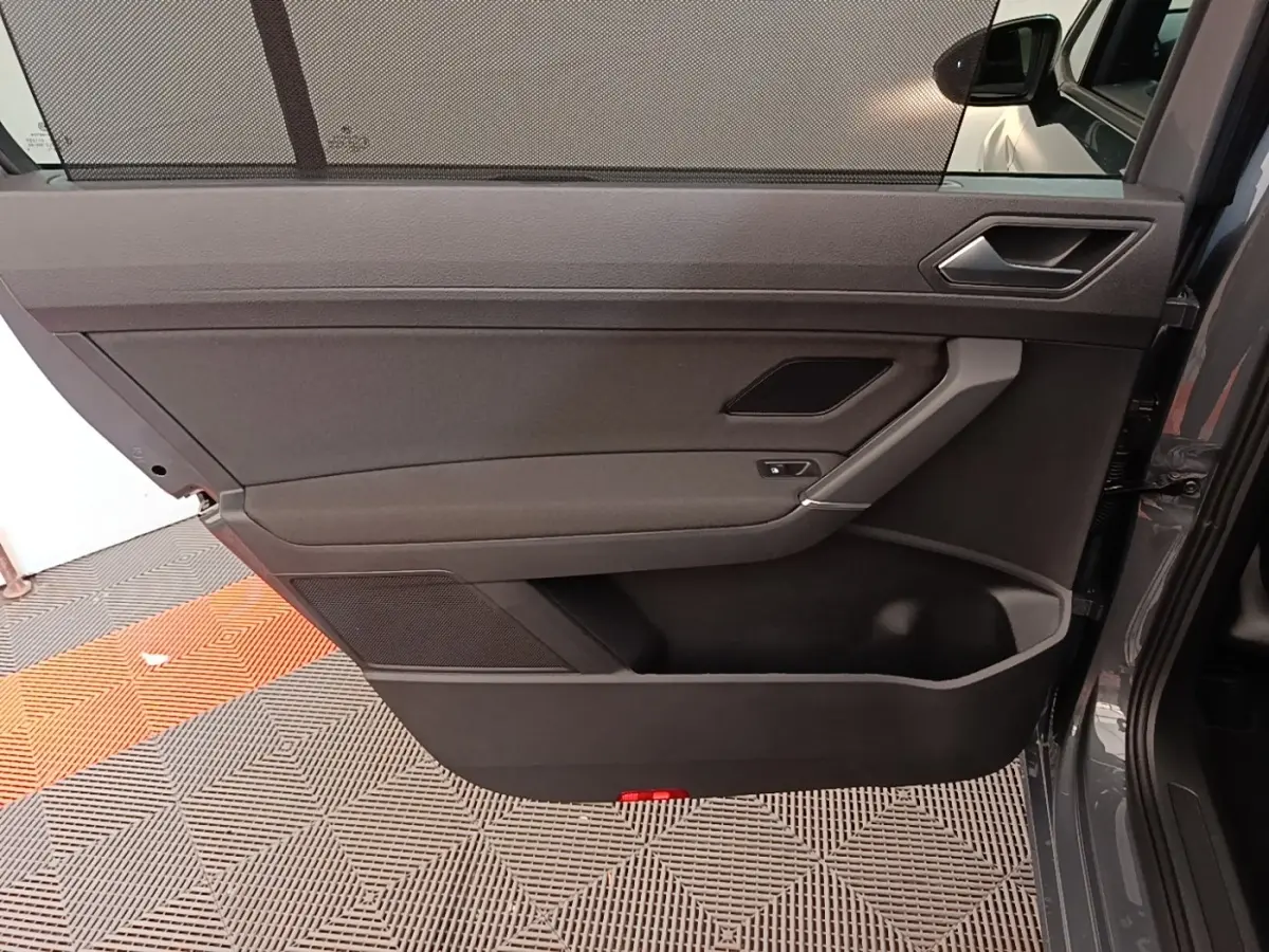 Vue intérieure de la porte arrière droite du Volkswagen Touran gris clair, avec poignée et haut-parleur intégrés.