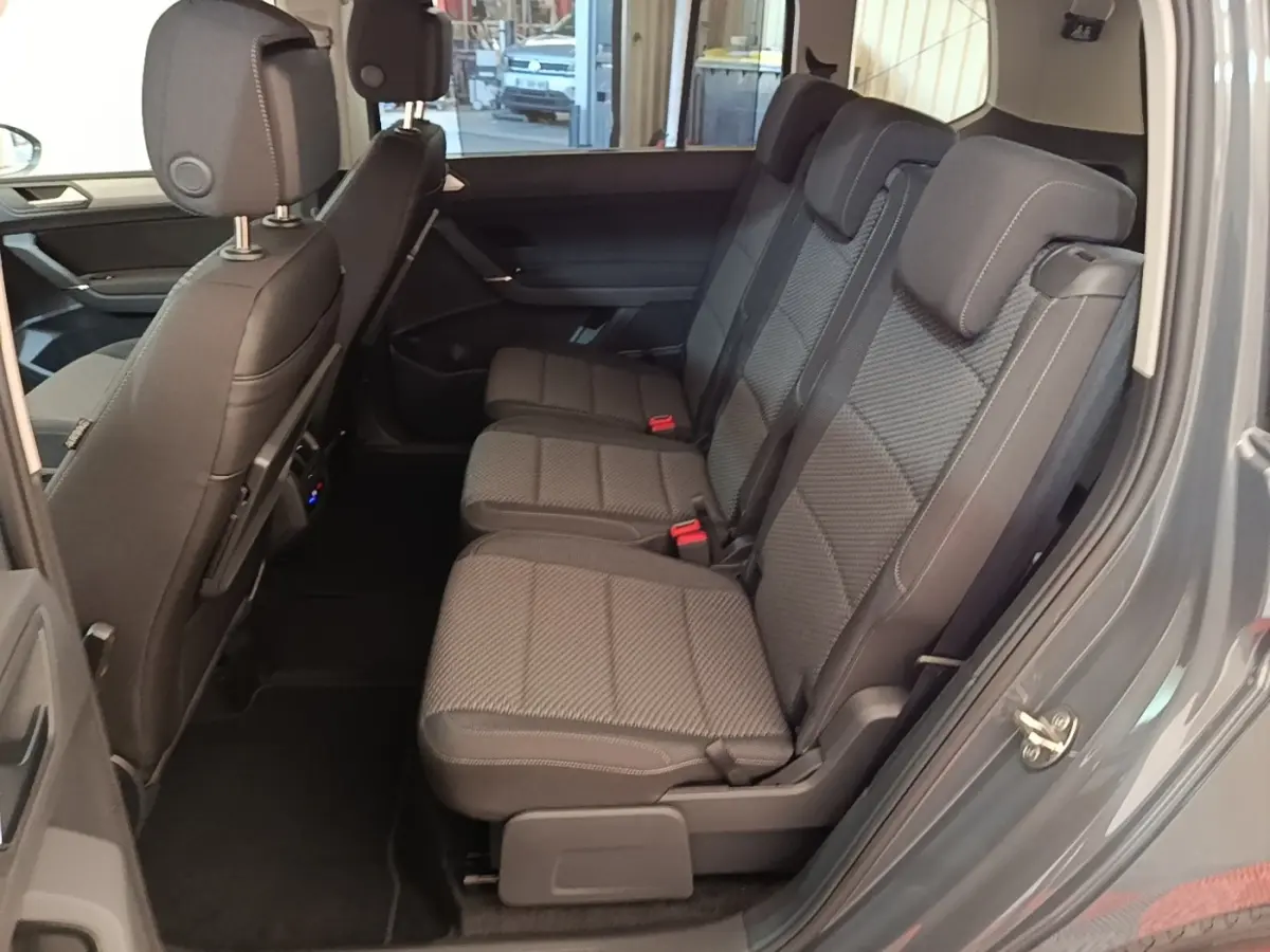 Vue latérale intérieure du siège arrière droit gris foncé du Volkswagen Touran 2024, montrant trois places avec appuie-têtes.