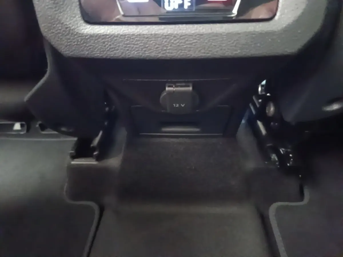 Prise 12V sous la console centrale arrière du Volkswagen Touran gris clair, vue rapprochée du plancher.