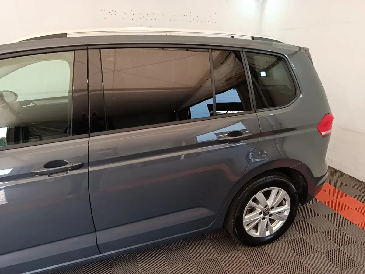 Vue latérale droite d'un Volkswagen Touran gris clair 2024 avec vitres teintées et jantes alliage.