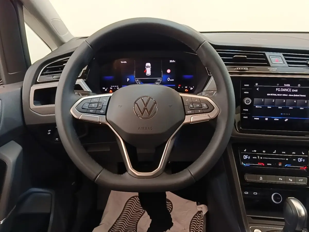 Vue intérieure centrée sur le volant cuir noir et le combiné numérique du Volkswagen Touran 2024, tableau de bord moderne.