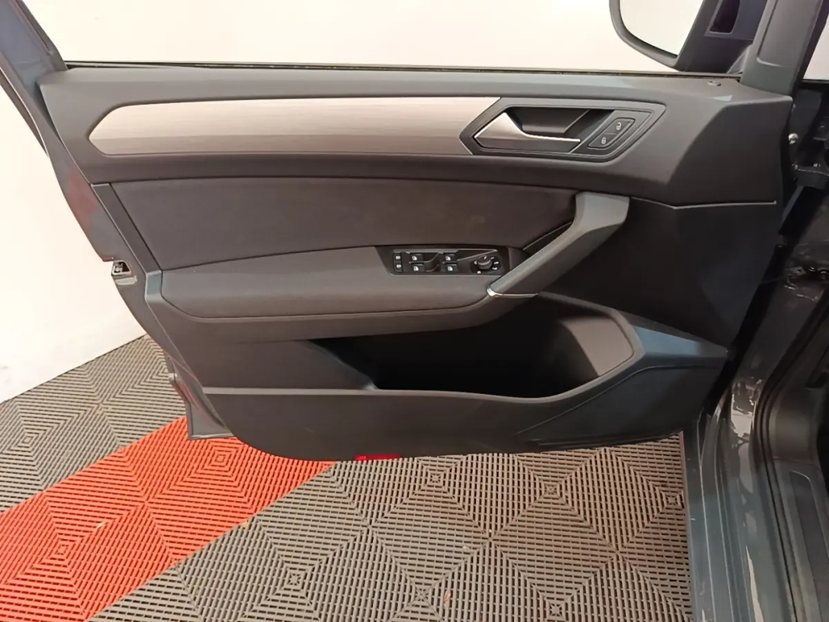 Vue côté gauche de la porte avant gris clair du Volkswagen Touran 2024 avec commandes électriques et insert bois.