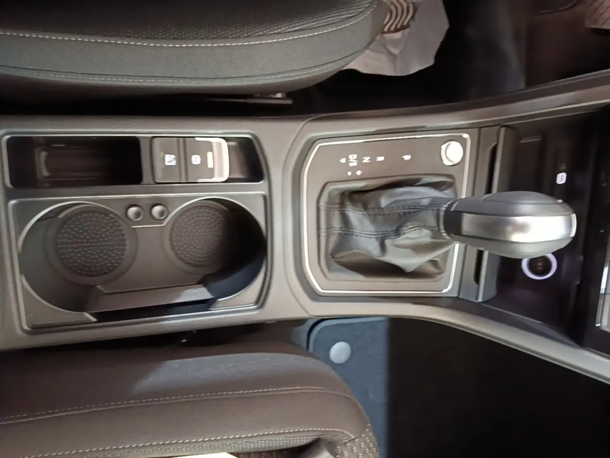 Vue rapprochée de la console centrale du Volkswagen Touran 2024 avec levier de vitesse automatique et porte-gobelets noirs.