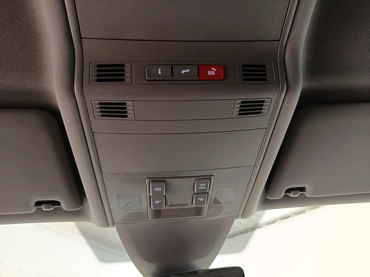 Vue intérieure du plafonnier gris clair du Volkswagen Touran 2024 avec boutons SOS et commandes d’éclairage.