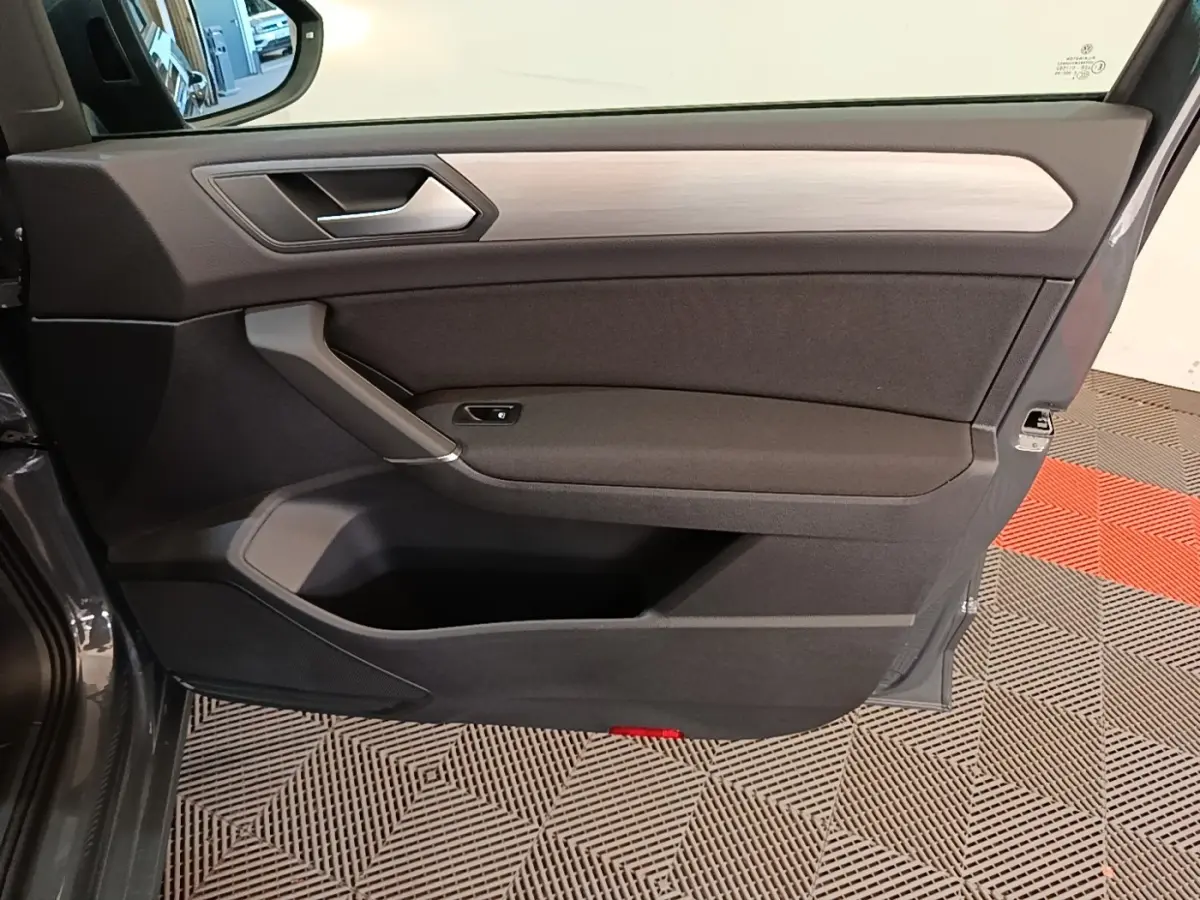 Vue intérieure de la porte avant gauche du Volkswagen Touran gris clair 2024 avec insert décoratif bois clair.