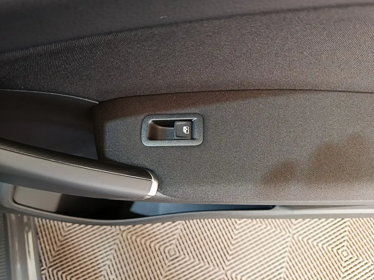 Détail de la poignée intérieure et bouton de verrouillage de porte du Volkswagen Touran gris clair 2024.