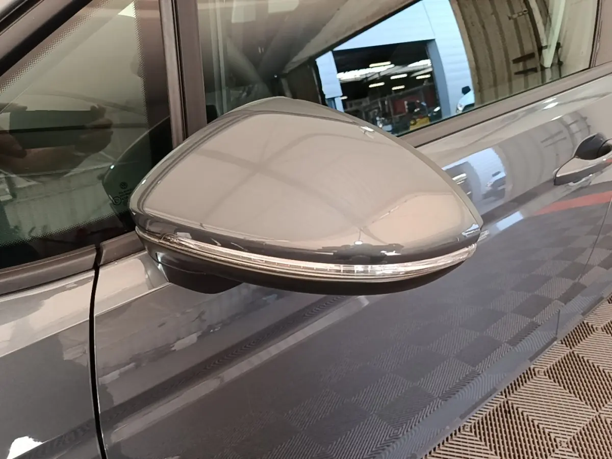 Rétroviseur droit gris clair du Volkswagen Touran 2024 avec clignotant intégré, vue rapprochée côté passager.