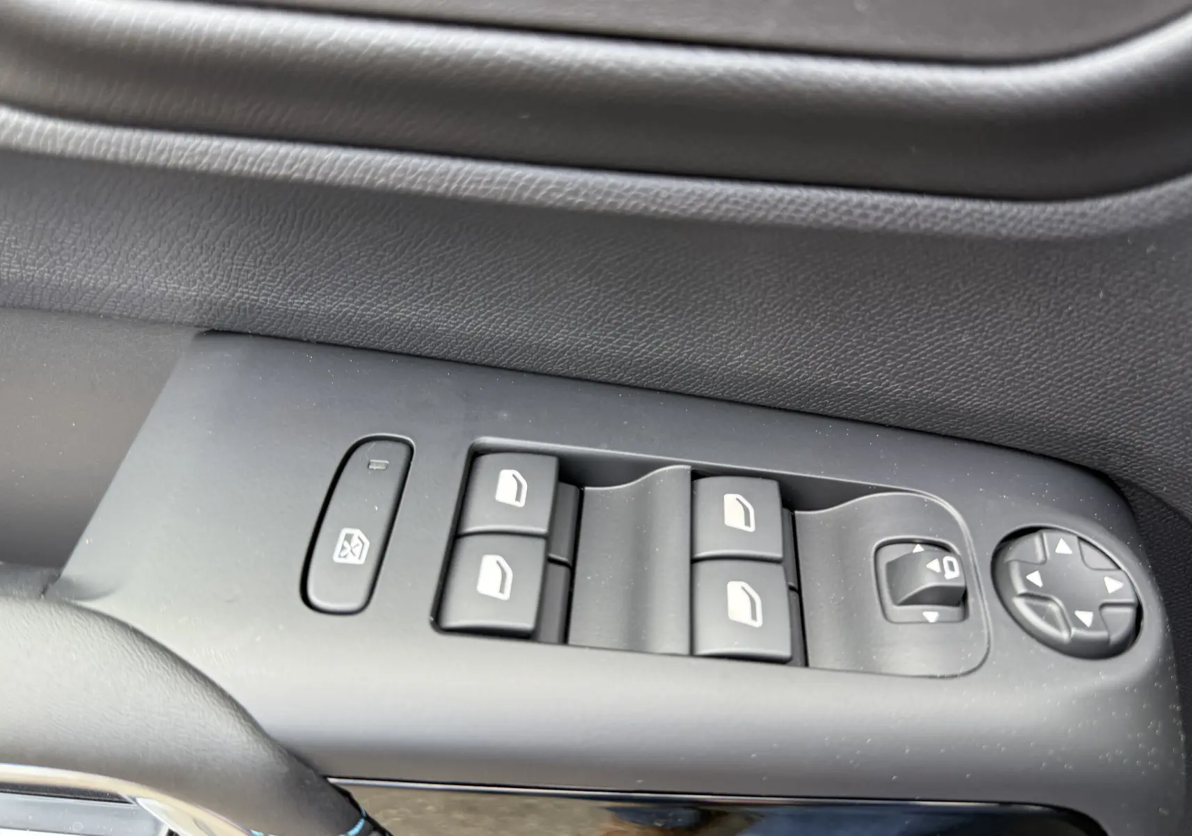 Gros plan sur les commandes de lève-vitres et réglages des rétroviseurs côté conducteur, finition cuir noir.