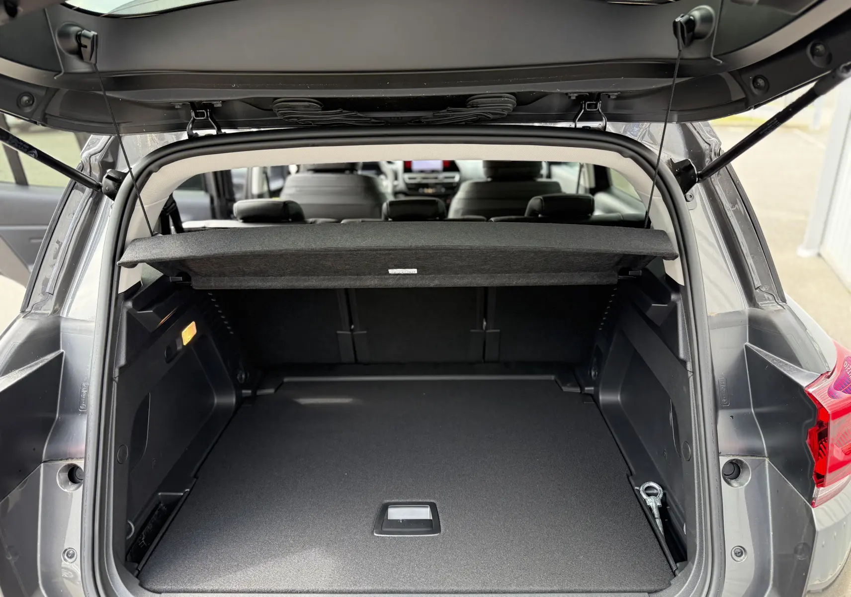 Coffre ouvert vu de l'arrière d'un Citroën C5 Aircross gris platinium métal, espace de chargement spacieux et bien agencé.