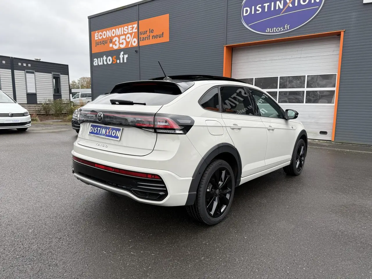 Volkswagen Taigo blanc vue 3/4 arrière droit avec toit noir et jantes noires brillantes sur parking extérieur