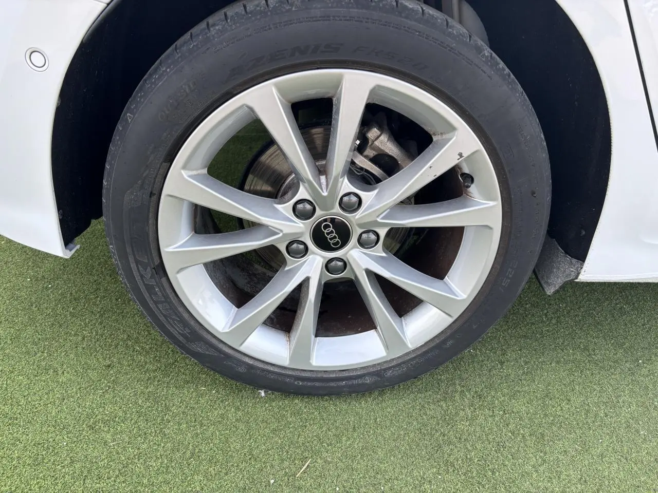 Gros plan sur la jante alliage 5 branches parallèles de l'Audi A3 Sportback blanc Arkona côté avant droit.