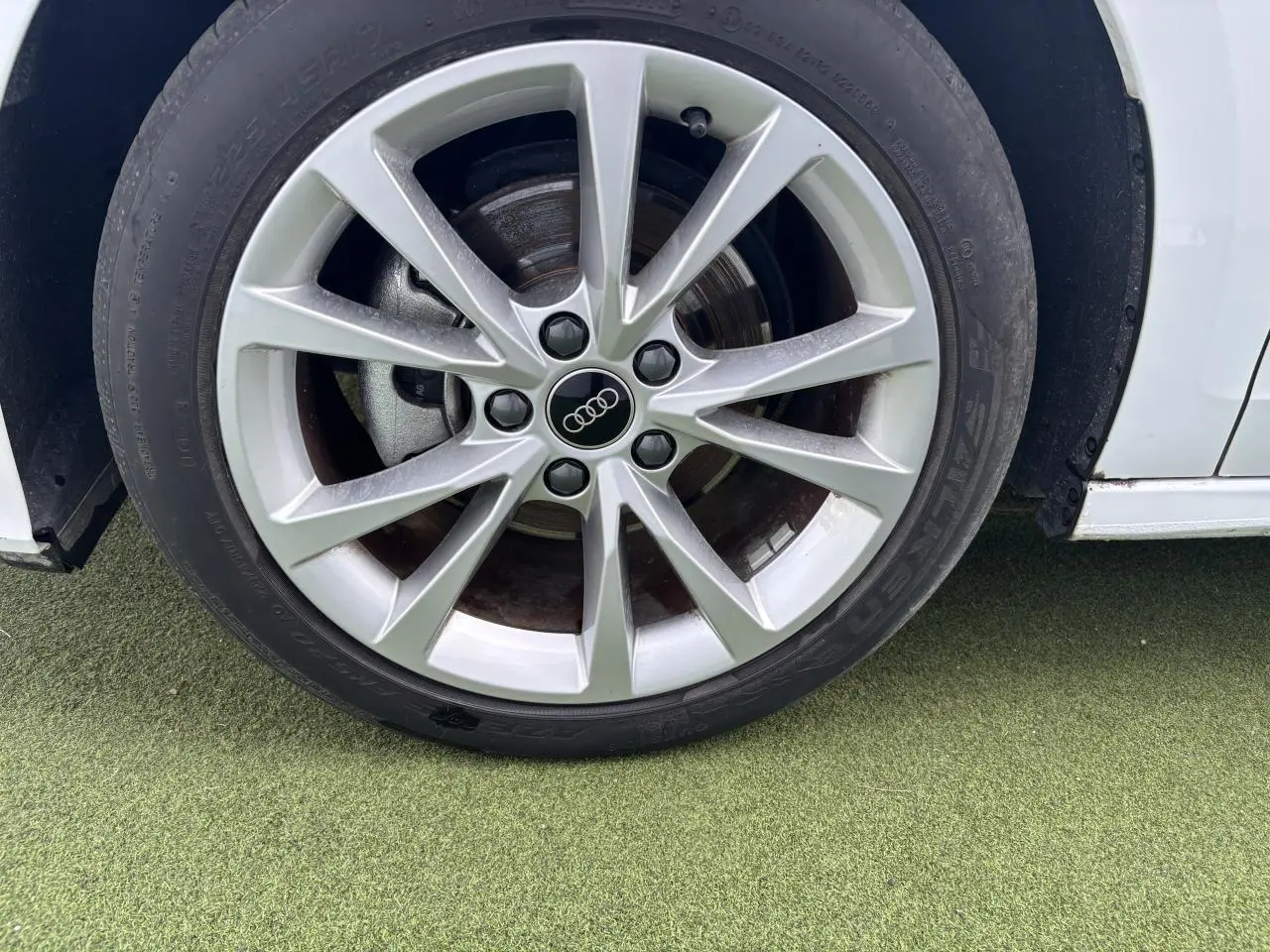 Gros plan sur la jante alliage 5 branches parallèles de l'Audi A3 Sportback blanc Arkona côté avant droit.