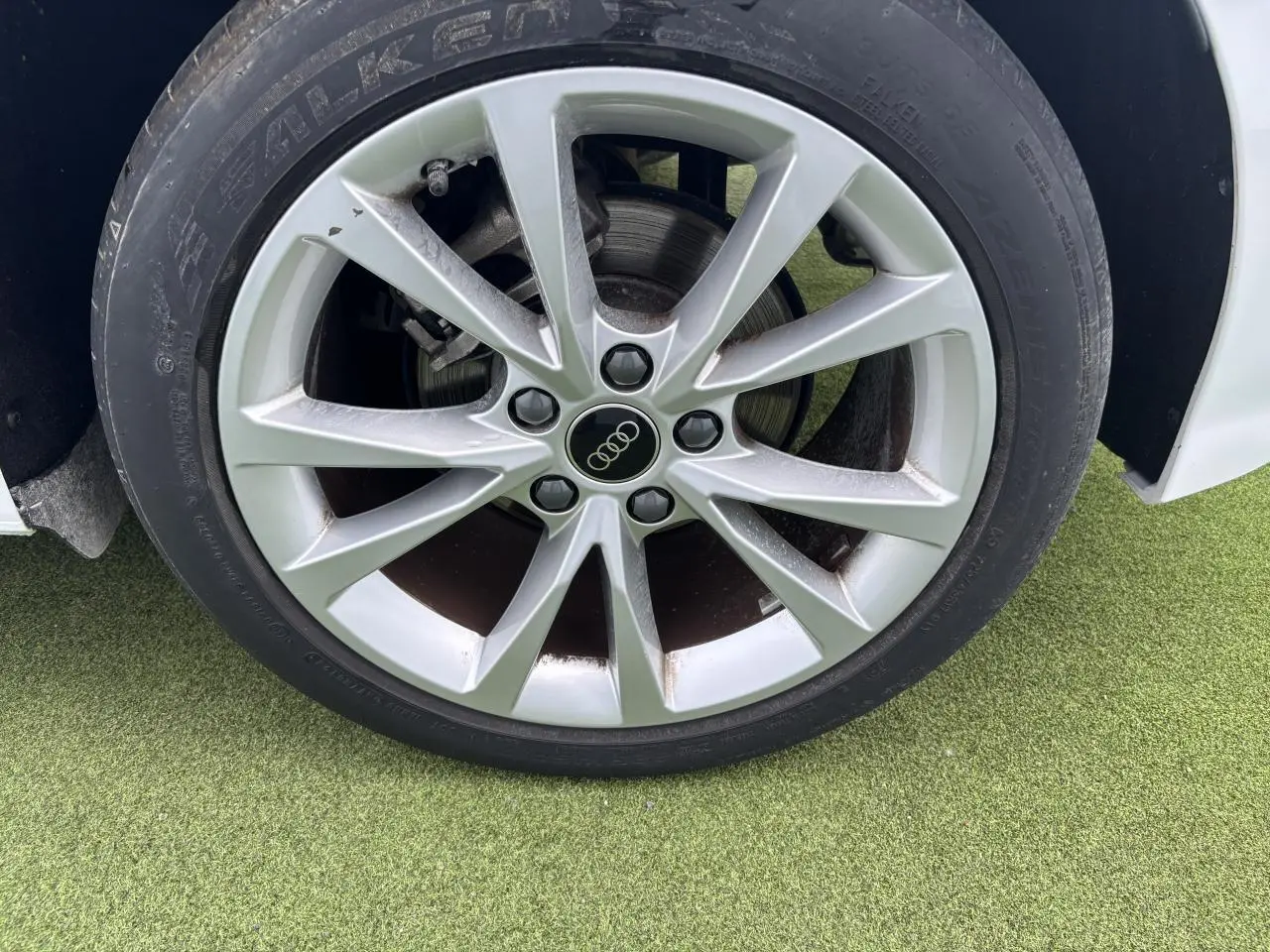 Gros plan sur la jante alliage 5 branches parallèles de couleur argentée d'une Audi A3 Sportback blanche.