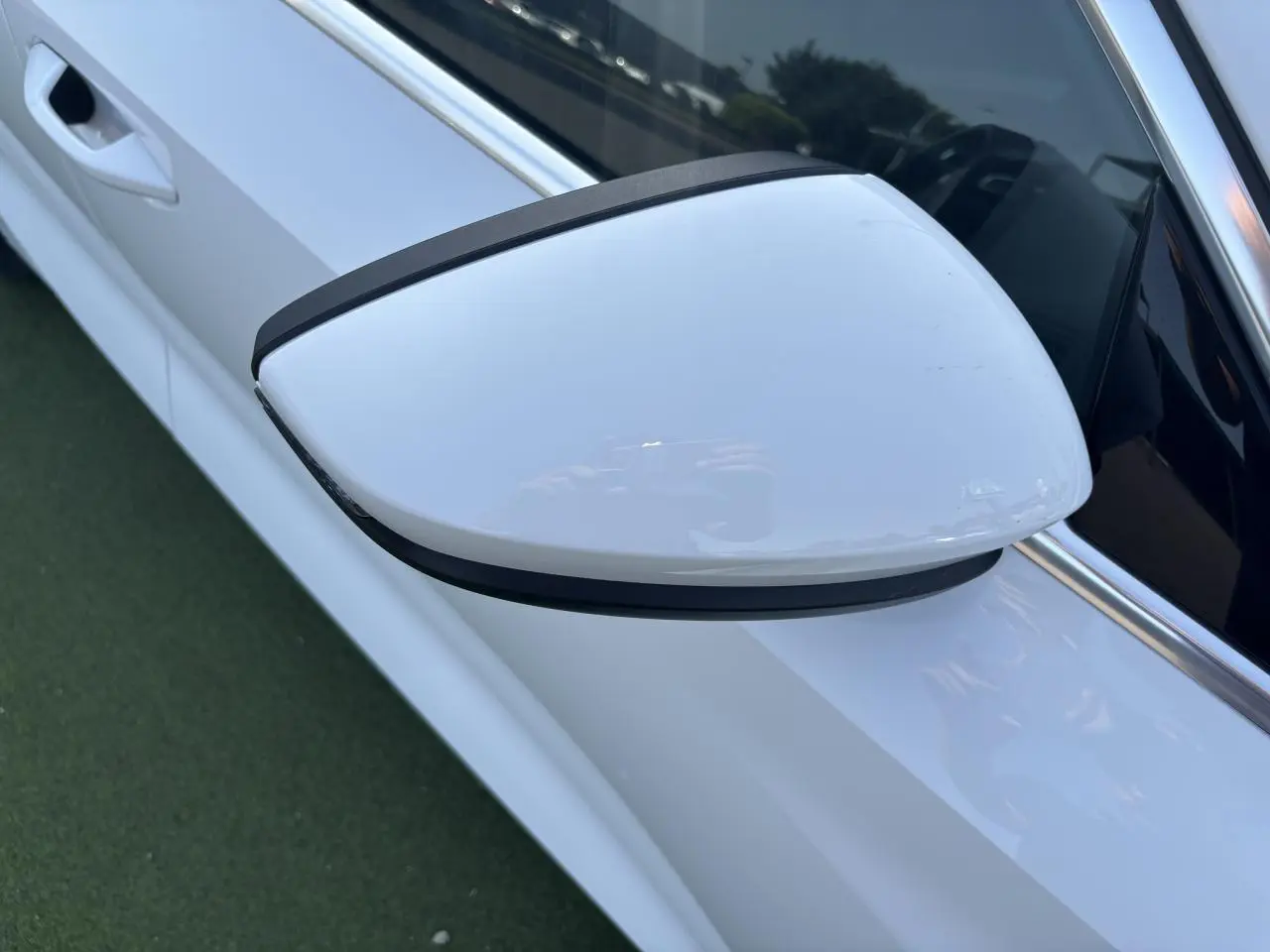 Rétroviseur côté gauche blanc Arkona de l'Audi A3 Sportback 2024, avec poignée de porte visible en arrière-plan.