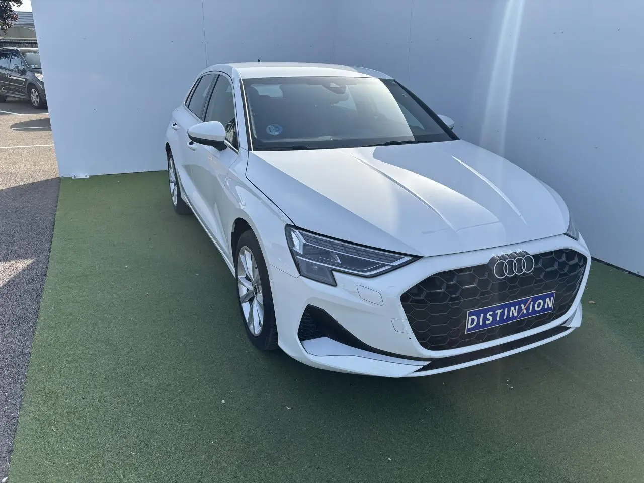 Audi A3 Sportback blanc Arkona vue 3/4 avant droit avec calandre noire hexagonale et phares LED distinctifs.