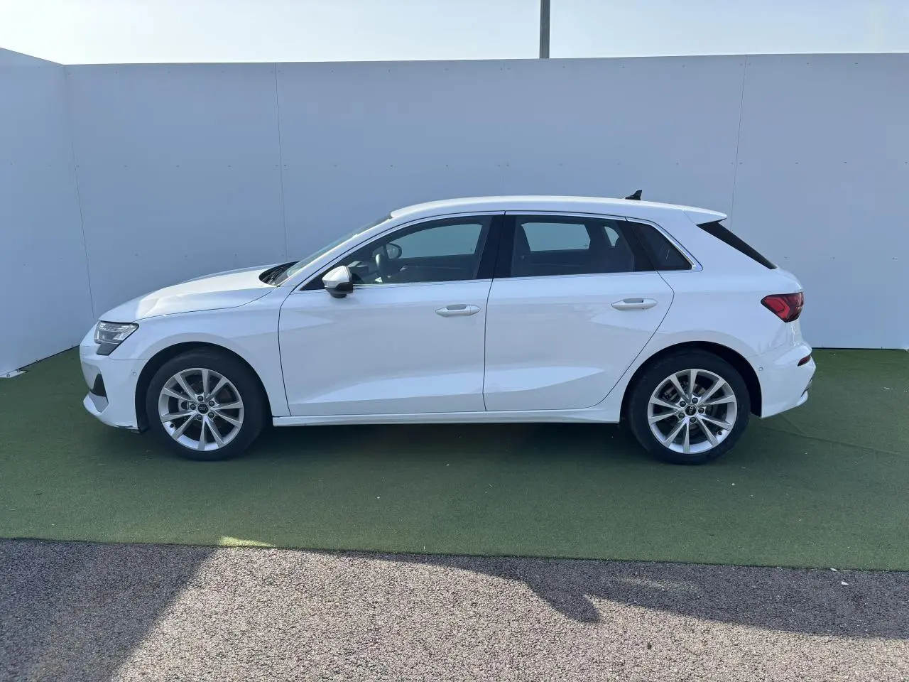 Profil côté gauche d'une Audi A3 Sportback blanche Arkona 2024 avec jantes alliage 5 branches parallèles.