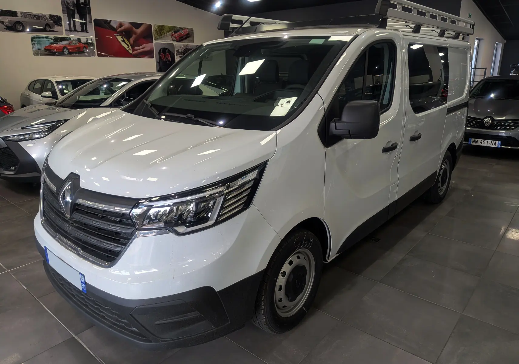 Renault Trafic Cabine Approfondie blanc minéral vu en 3/4 avant droit avec galerie de toit en intérieur showroom.