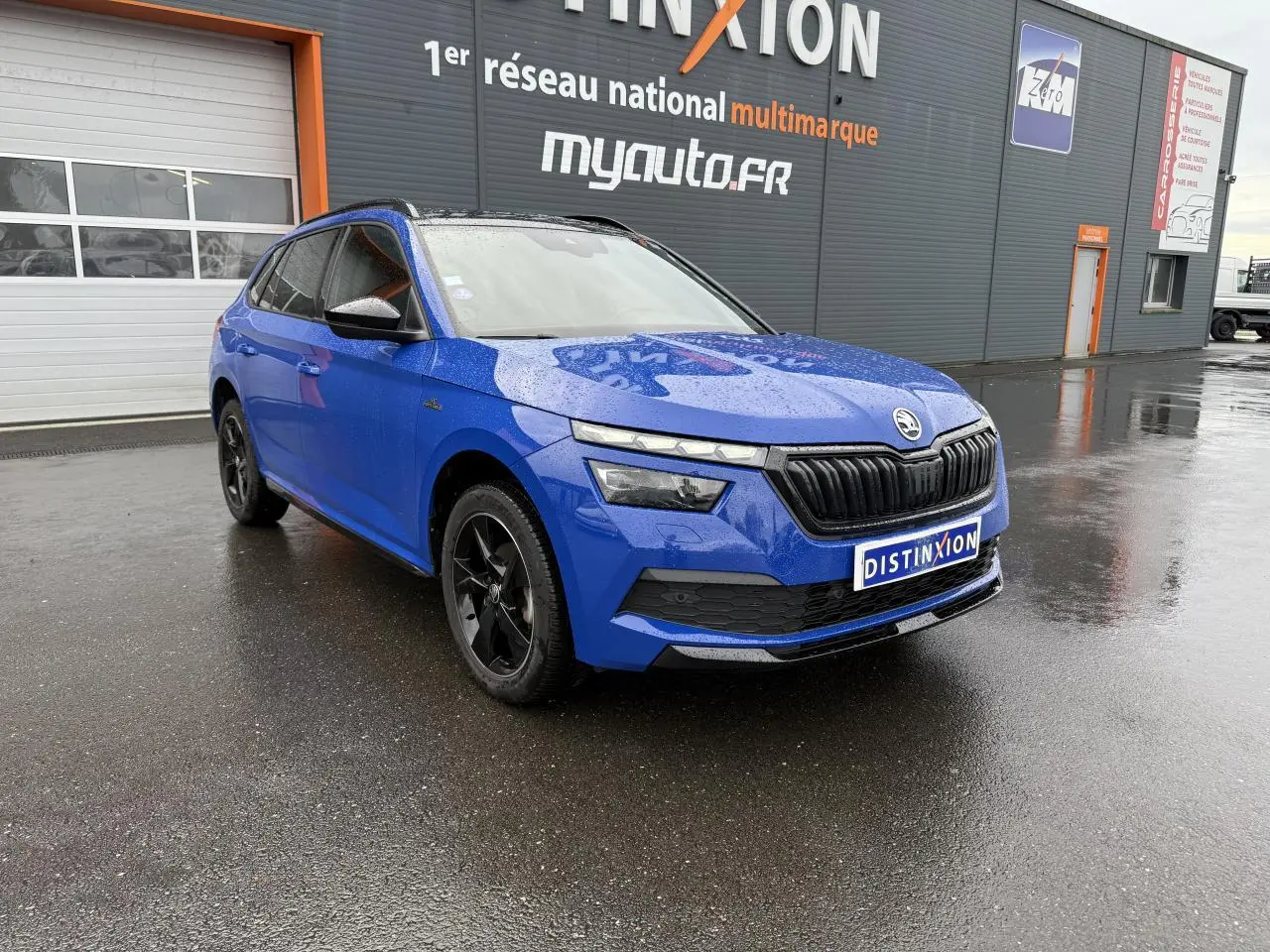 Vue 3/4 avant gauche d'un Skoda Kamiq Monte-Carlo bleu Energy avec jantes noires et calandre noire brillante.