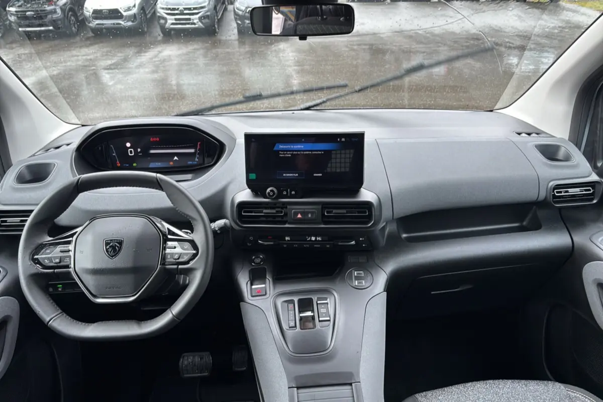 Vue intérieure du tableau de bord et volant cuir multifonctions du Peugeot Rifter gris Artense 2026 version BlueHDi 130 EAT8 Allure.