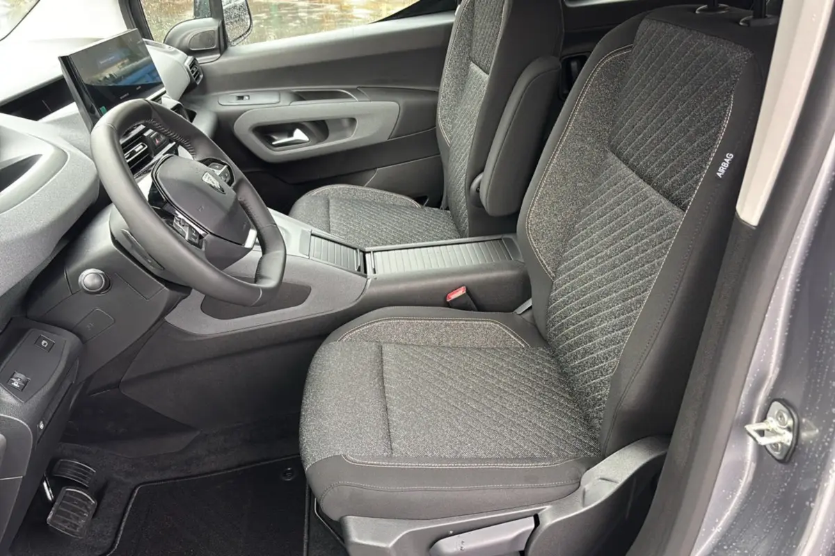 Vue intérieure côté conducteur du Peugeot Rifter gris artense 2026, avec sièges tissu et volant cuir multifonctions.