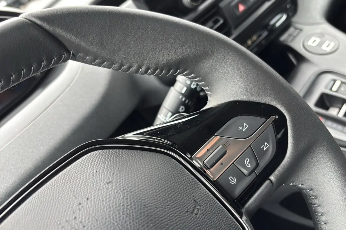 Gros plan sur le volant cuir multifonctions noir du Peugeot Rifter, avec commandes audio et téléphone intégrées.