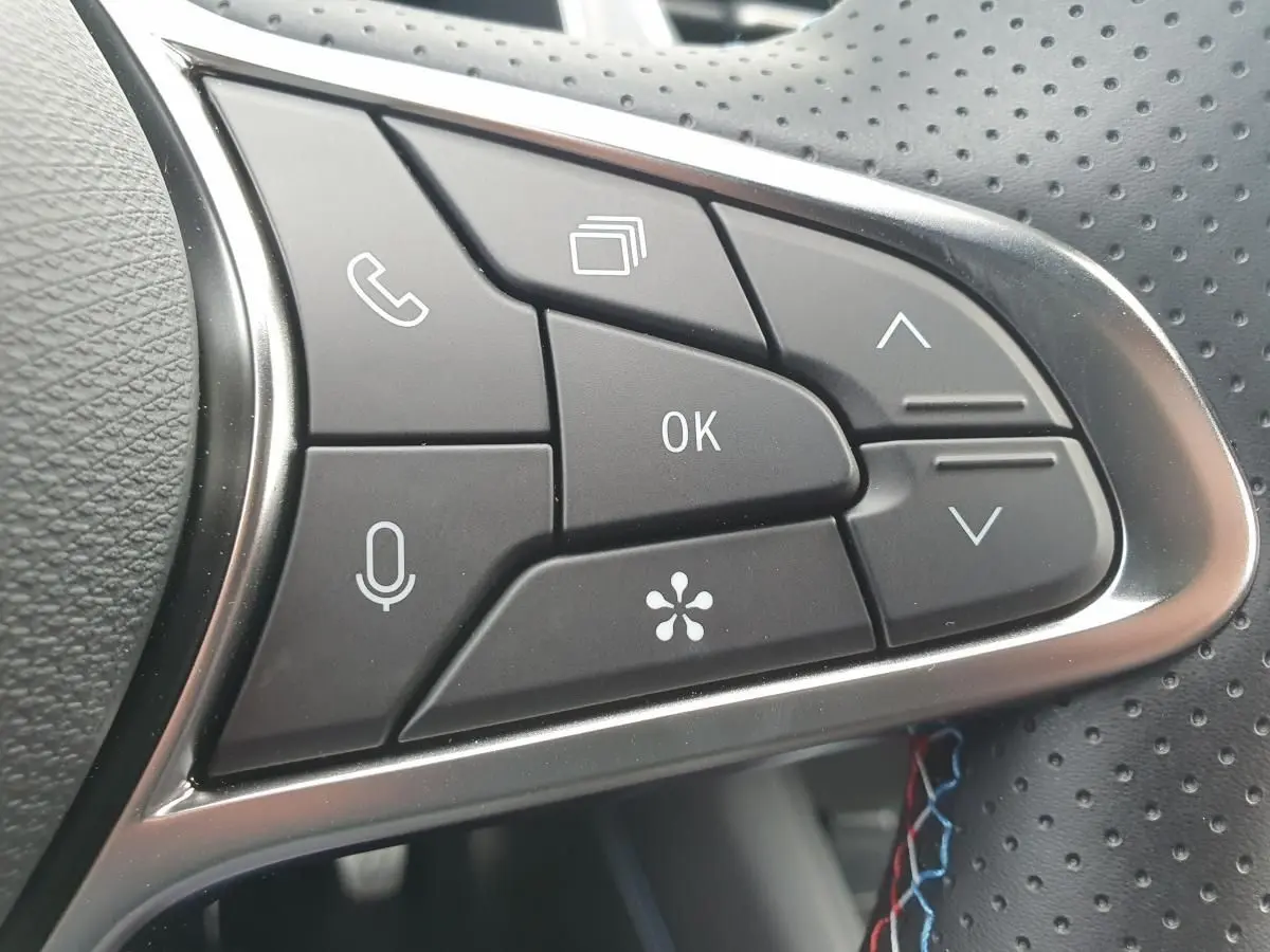Gros plan sur les commandes multifonctions du volant perforé du Renault Captur Bleu Iron 2026.