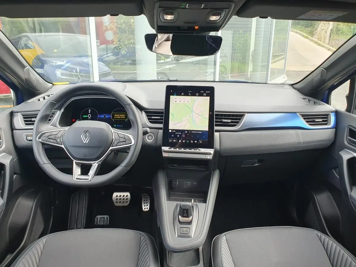Vue intérieure avant du Renault Captur bleu Iron 2026, tableau de bord avec écran tactile vertical et volant multifonction.