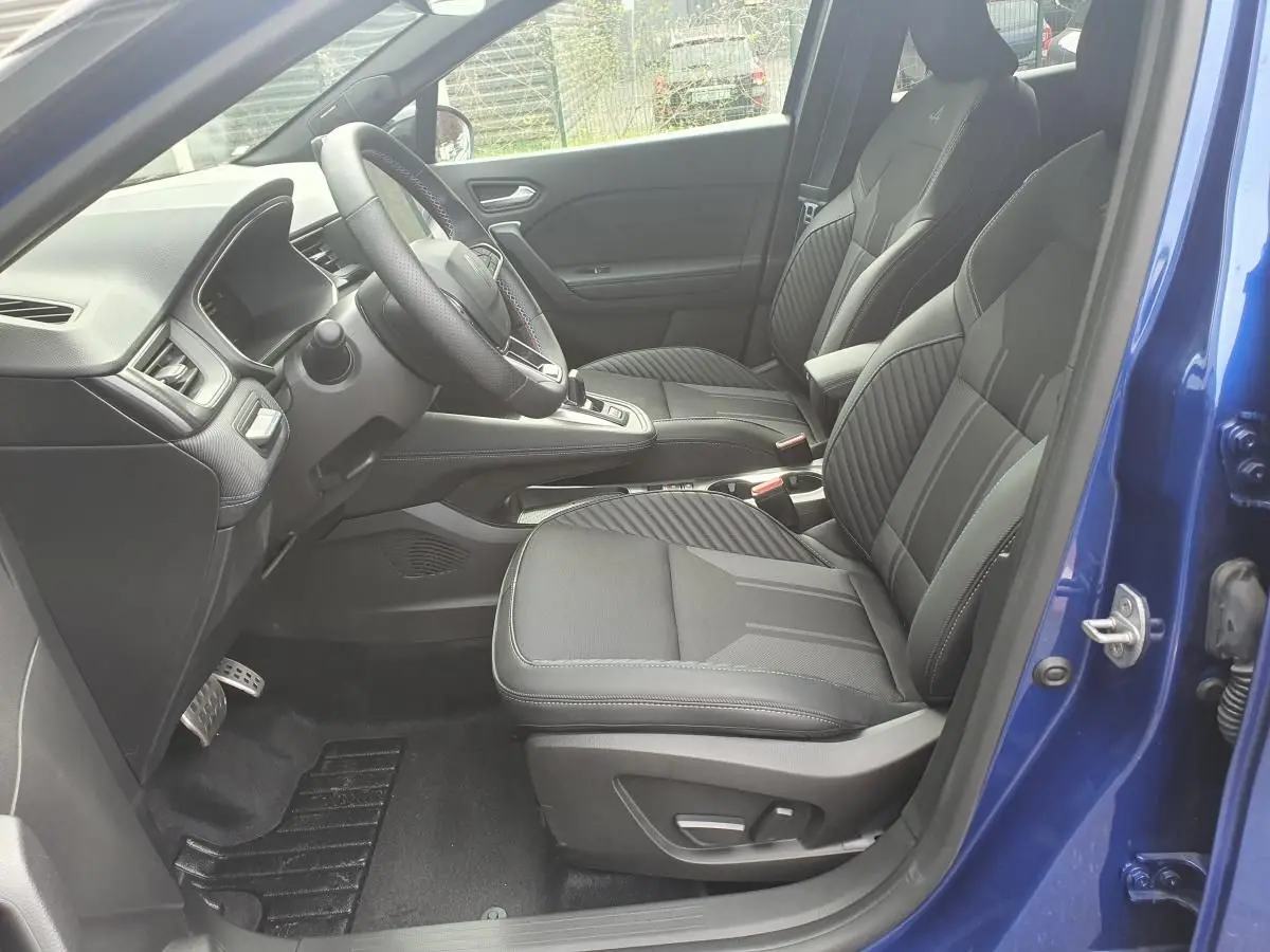 Vue intérieure côté conducteur du Renault Captur bleu iron 2026, sièges noirs et tableau de bord moderne.