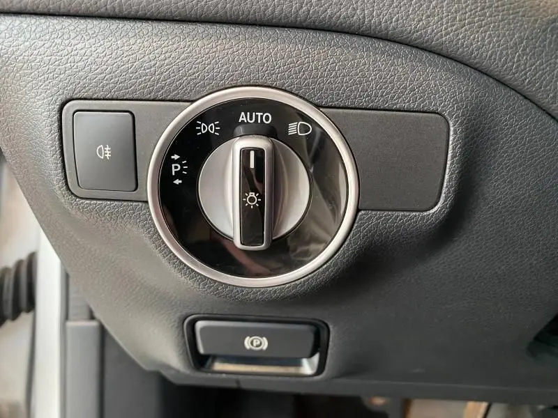 Gros plan sur le bouton de commande des phares et le frein à main électrique d'une Mercedes GLA 200 Sensation 2017.