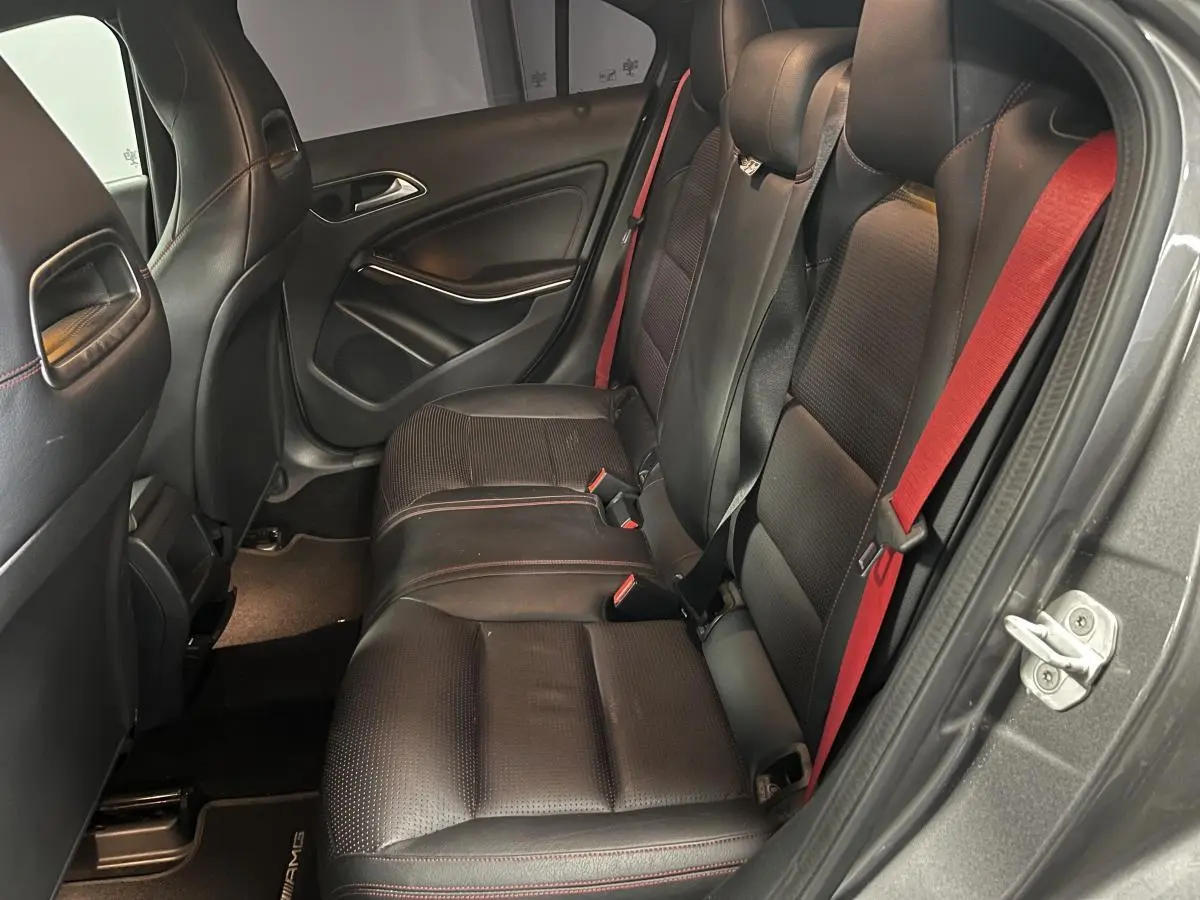 Vue intérieure côté droit des sièges arrière noirs avec ceintures rouges d'une Mercedes Classe A 45 AMG gris métallisé 2015.
