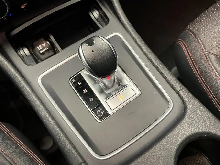 Le levier de vitesses automatique noir avec surpiqûres rouges sur l'accoudoir d'une Mercedes Classe A AMG 2015.