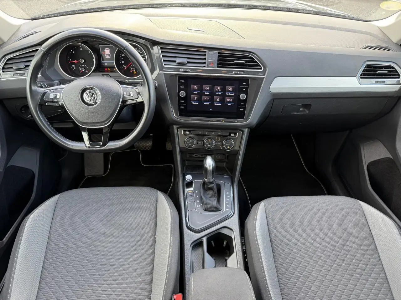 Vue intérieure avant du Volkswagen Tiguan 2018, tableau de bord et console centrale avec écran tactile et volant cuir multifonctions.