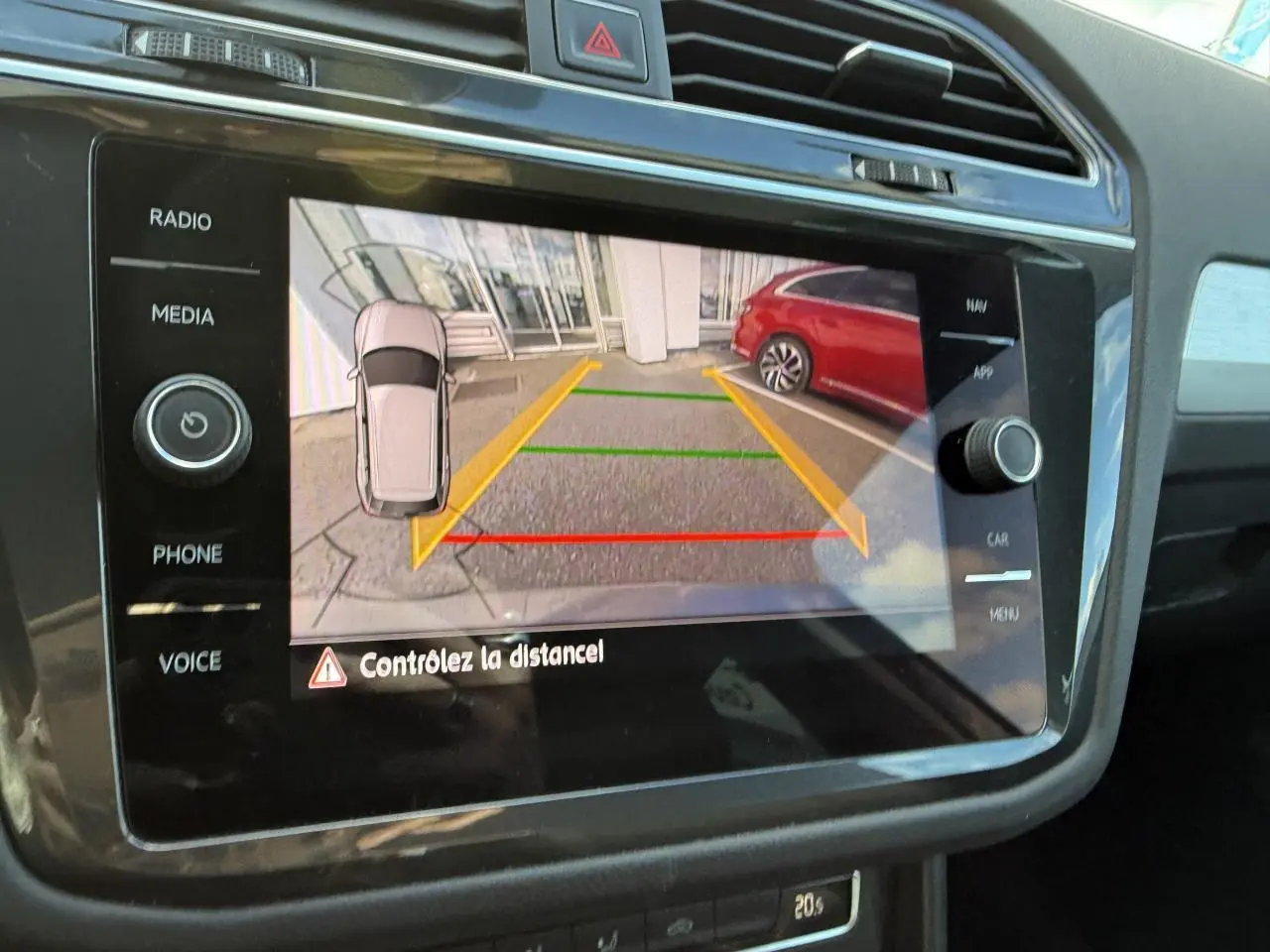 Écran multimédia montrant la caméra de recul du Volkswagen Tiguan gris Indium avec lignes de guidage colorées.