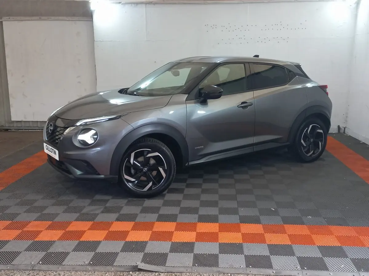 Nissan Juke Hybrid 143 Business+ gris foncé, vue 3/4 avant droit, jantes noires à motifs argentés.