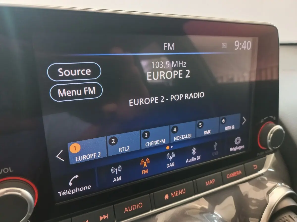 Écran tactile central de la Nissan Juke Hybrid 2023 affichant la radio FM Europe 2, avec commandes audio visibles.