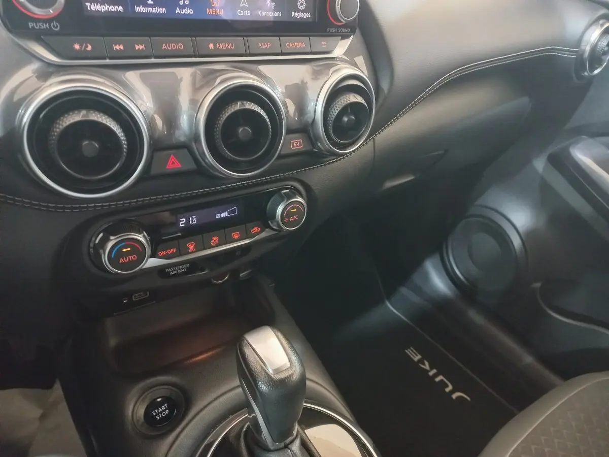 Vue intérieure côté passager du tableau de bord et console centrale noire du Nissan Juke Hybrid 143 Business+ 2023.