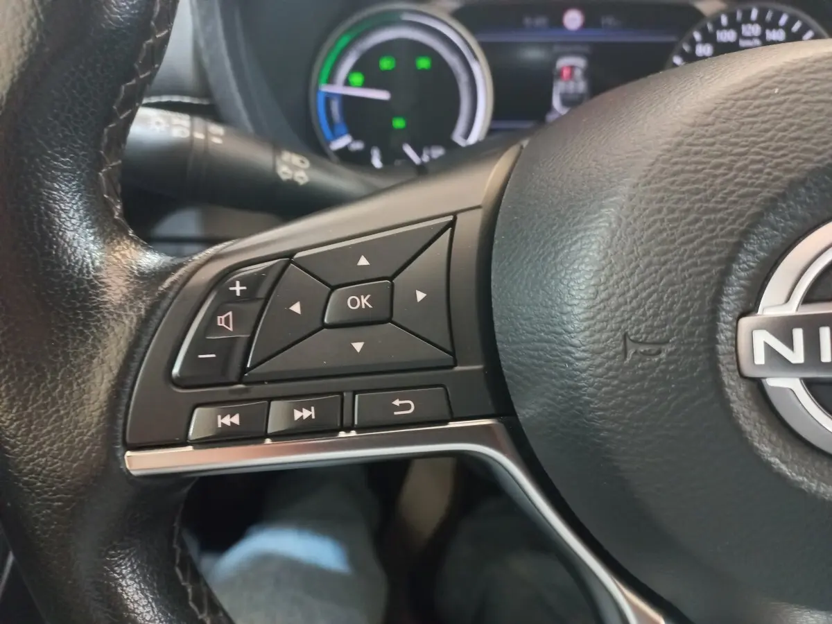 Gros plan sur le volant cuir et alu du Nissan Juke Hybrid 143 Business+ 2023, avec commandes multifonctions visibles.
